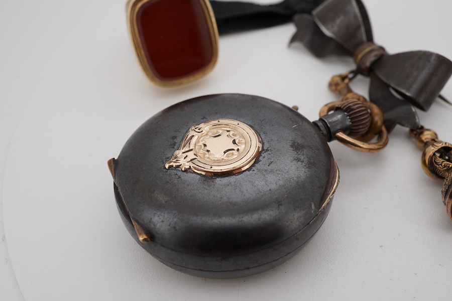 Three assorted yellow metal overlaid and gem set fob seals, including carnelian, largest 26mm, together with a gun metal fob watch, with yellow metal inset plaque.